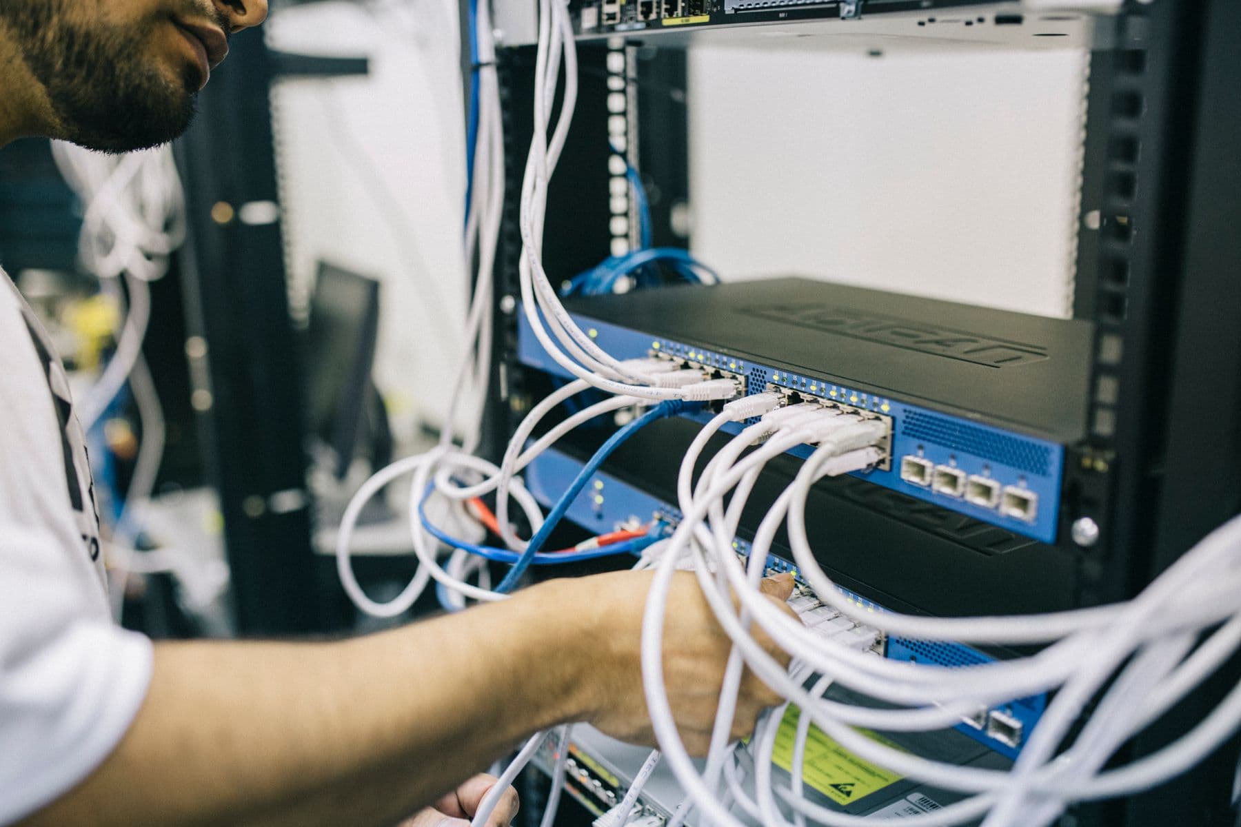 Technician configuring network cables at a commercial equipment rack
