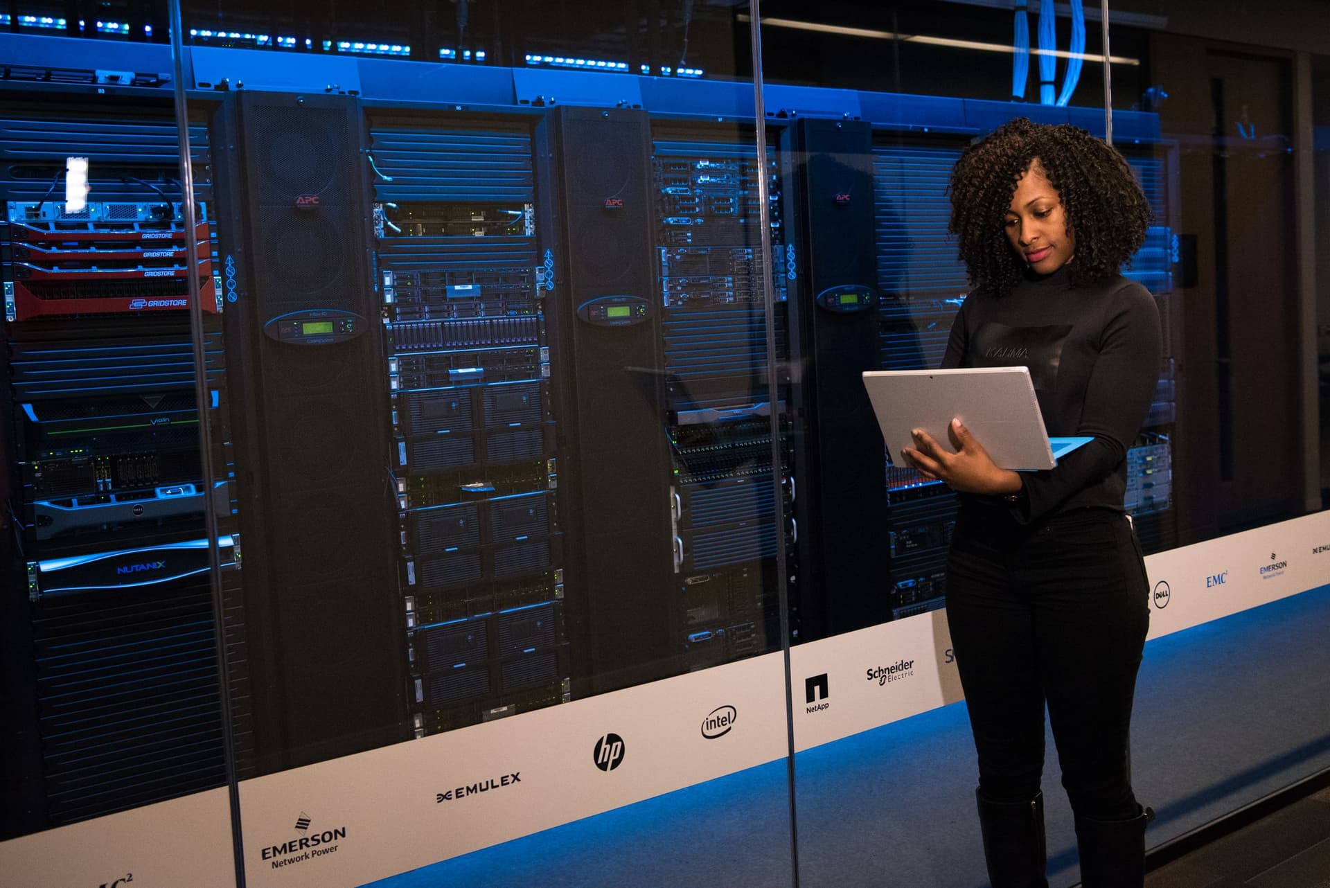 IT professional using a laptop in front of commercial server racks